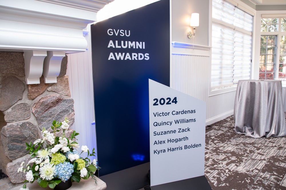Large blue and white sign with alumni award recipient names